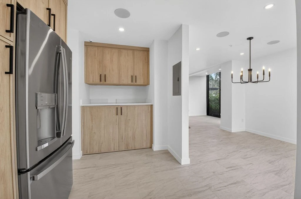 Matching custom bar cabinetry beside the kitchen and dining area in the Boca West condo