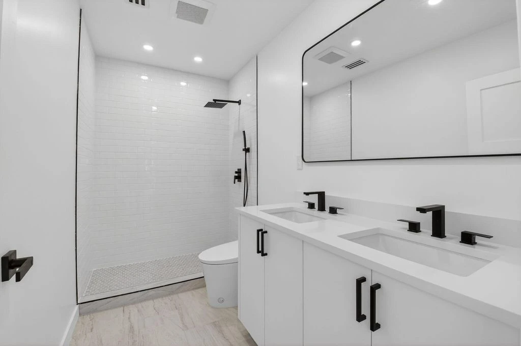 Completed Boca West bathroom with custom double vanity, large mirror and glass shower